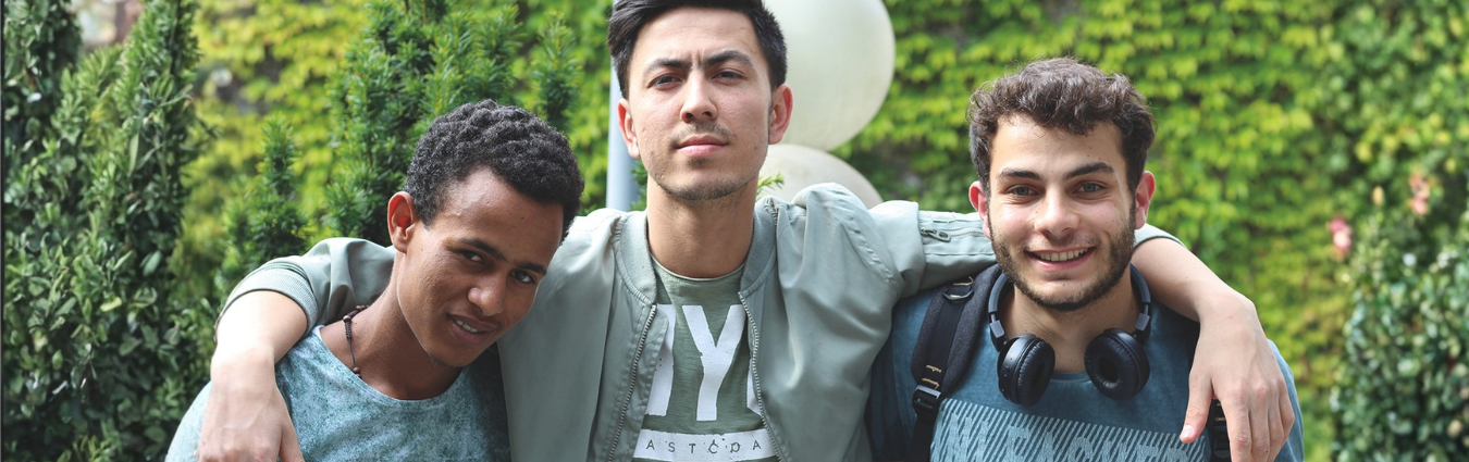 Auf dem Bild sieht man drei junge Männer mit Migrationshintergrund.