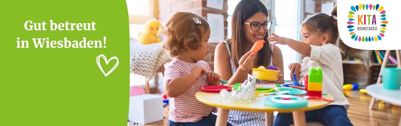 Auf dem Bild sieht man eine Situation aus einer Kindertagesstätte. Eine Frau mit Brille und braunen Haaren spielt mit zwei Kindern. Sie sitzt in der Mitte. Links und rechts von ihr sieht man zwei Kinder.