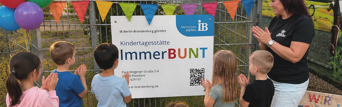 Kinder und eine Betreuungsperson stehen vor dem Eingangs­schild der Kindertagesstätte „ImmerBUNT“ in Potsdam. Das Schild der IB Berlin-Brandenburg gGmbH ist mit bunten Wimpeln dekoriert, mehrere Kinder klatschen und betrachten das Schild.