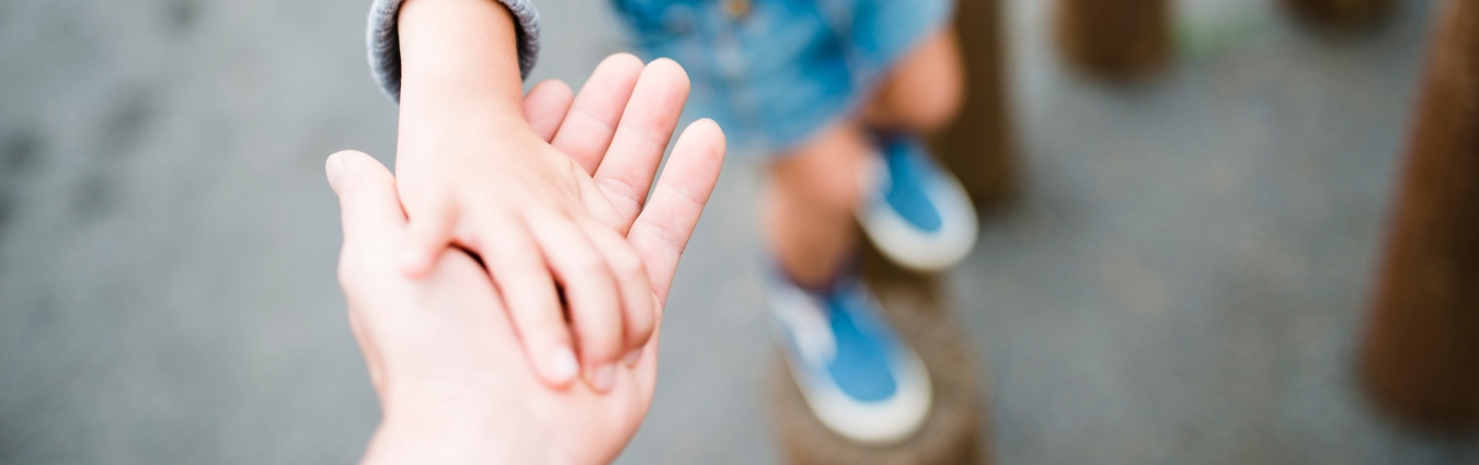 Eine Kinder- und eine Erwachsenenhand, die Händchen halten