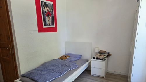 Ein Zimmer mit Bett, Nachttisch, Kleiderschrank und einem roten Bild an der Wand.
