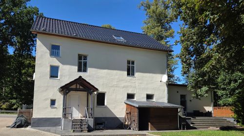 Ein großes, weißes Haus mit einem großen Hof und umgeben mit grünen Bäumen