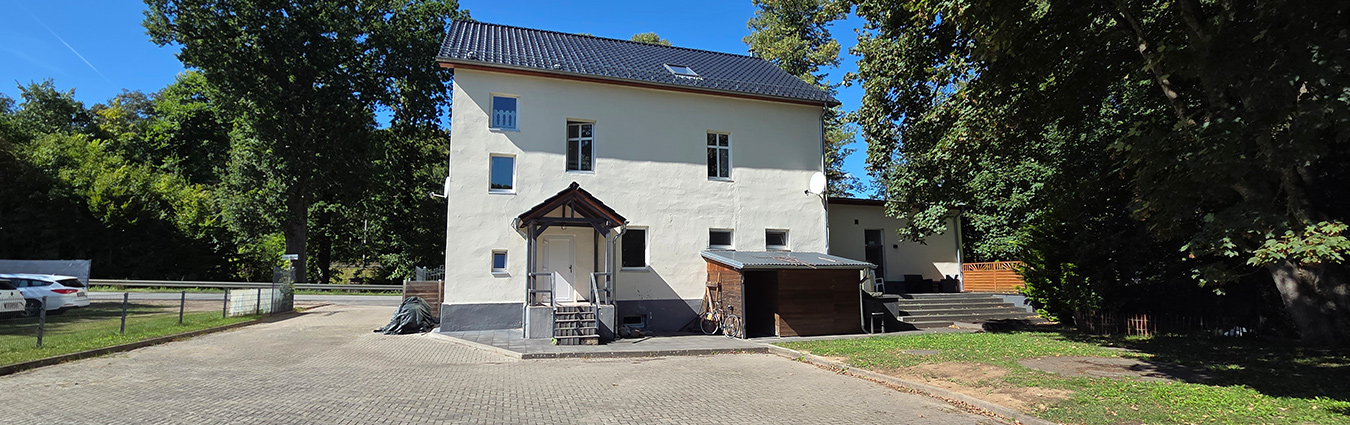 Ein großes, weißes Haus mit einem großen Hof und umgeben mit grünen Bäumen