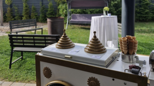 Man sieht einen Eiswagen auf dem Waffeln stehen in einem Gartenbereich.