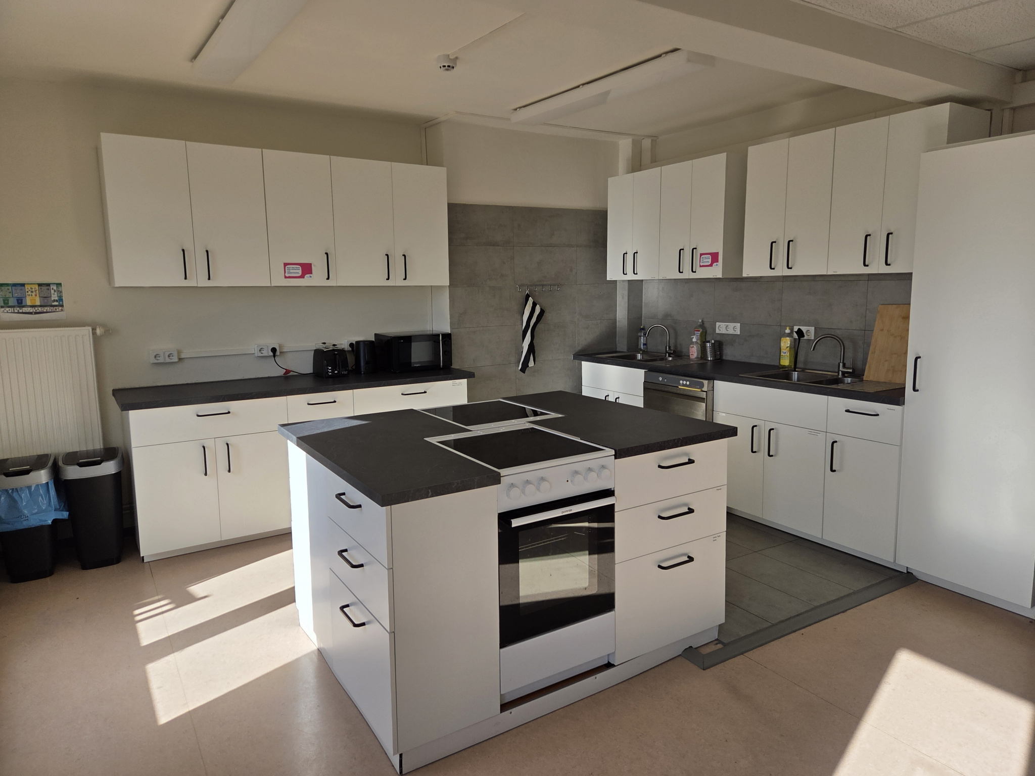 Eine helle Küche mit weißen Schränken und grauen Arbeitsflächen.