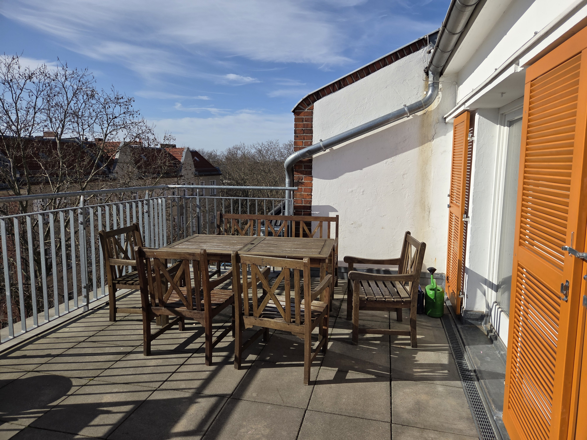 Eine Dachterrasse mit einem Holztisch und ein paar Stühlen